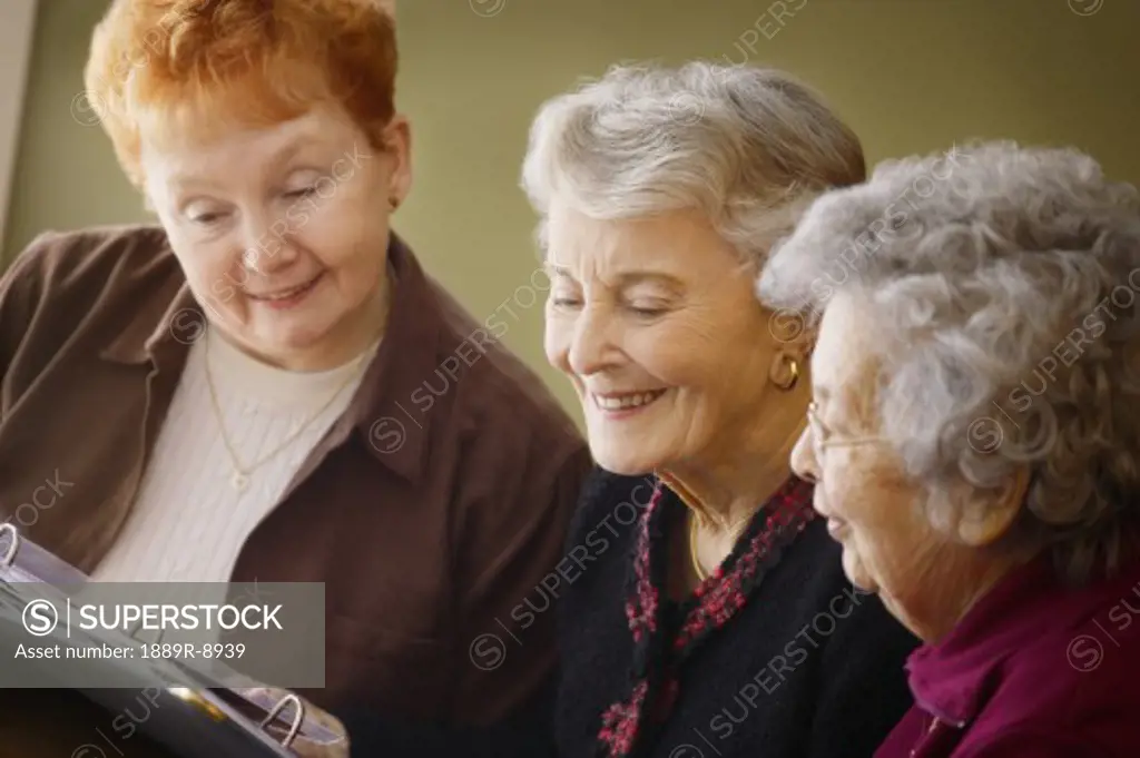 Three ladies looking at a photo album