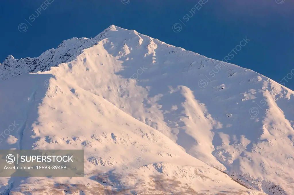 The setting sun highlights the ridgeline and cornices on Lark Mountain, Chugach National Forest, Winter, Moose Pass, Southcentral Alaska, USA.