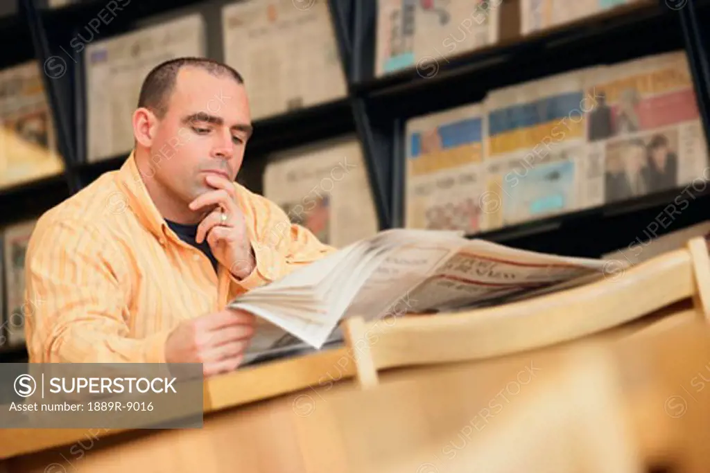 Man reading newspaper in library