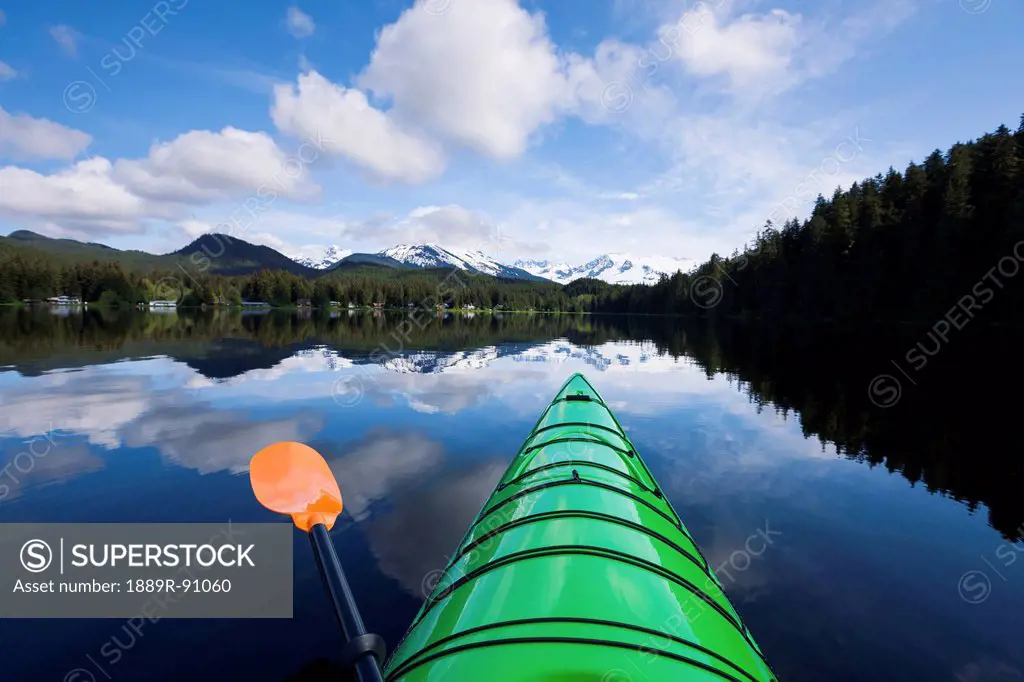 Green kayak on the tranquil water of auke lake with mendenhall glacier and towers in the distance;Alaska united states of america