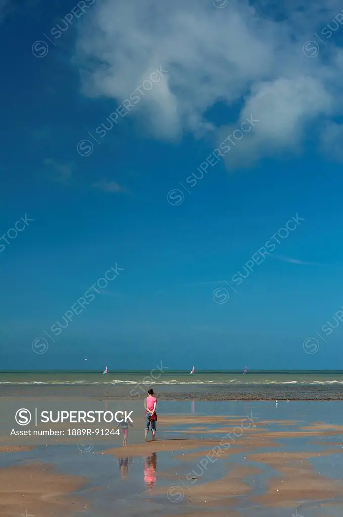 Mother and young daughter walking across sandy beach at low tide;Granville brittany france