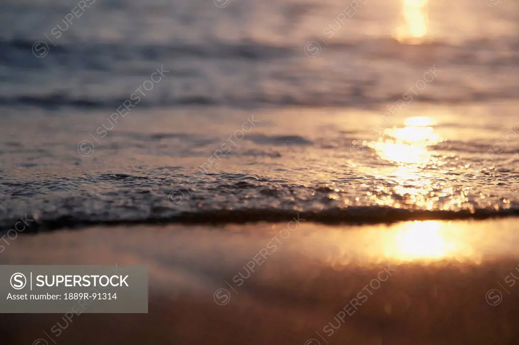 Sunlight reflecting off the water and wet sand at sunset;Honolulu hawaii united states of america