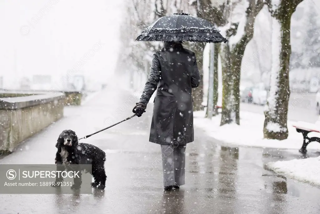 A woman walking her dog in a snowfall;Locarno ticino switzerland