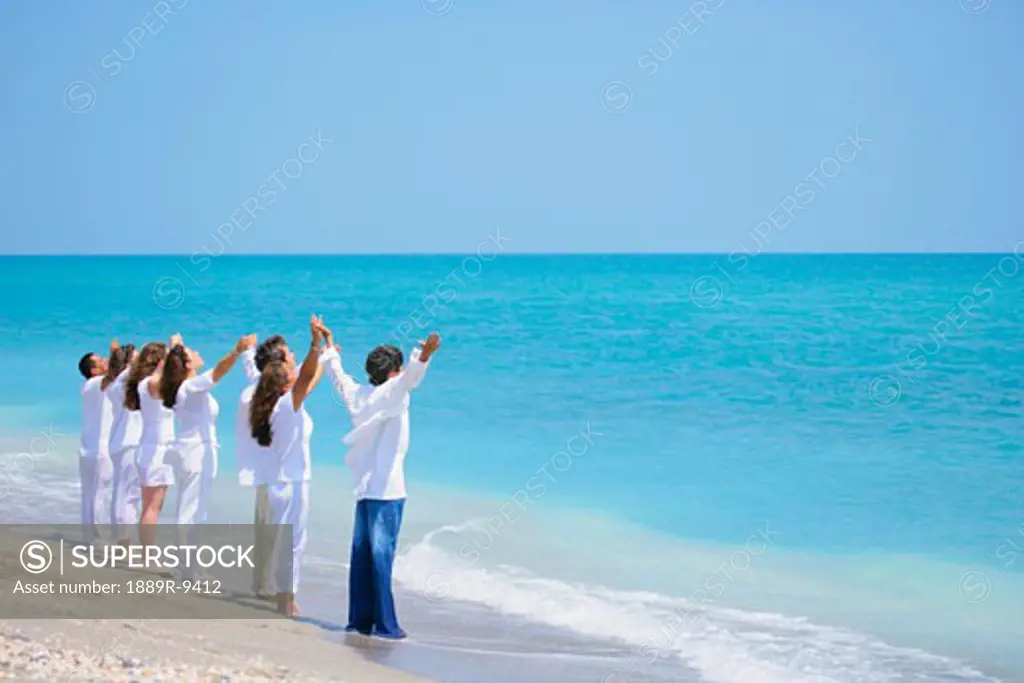 Group of people with arms raised at the seaside