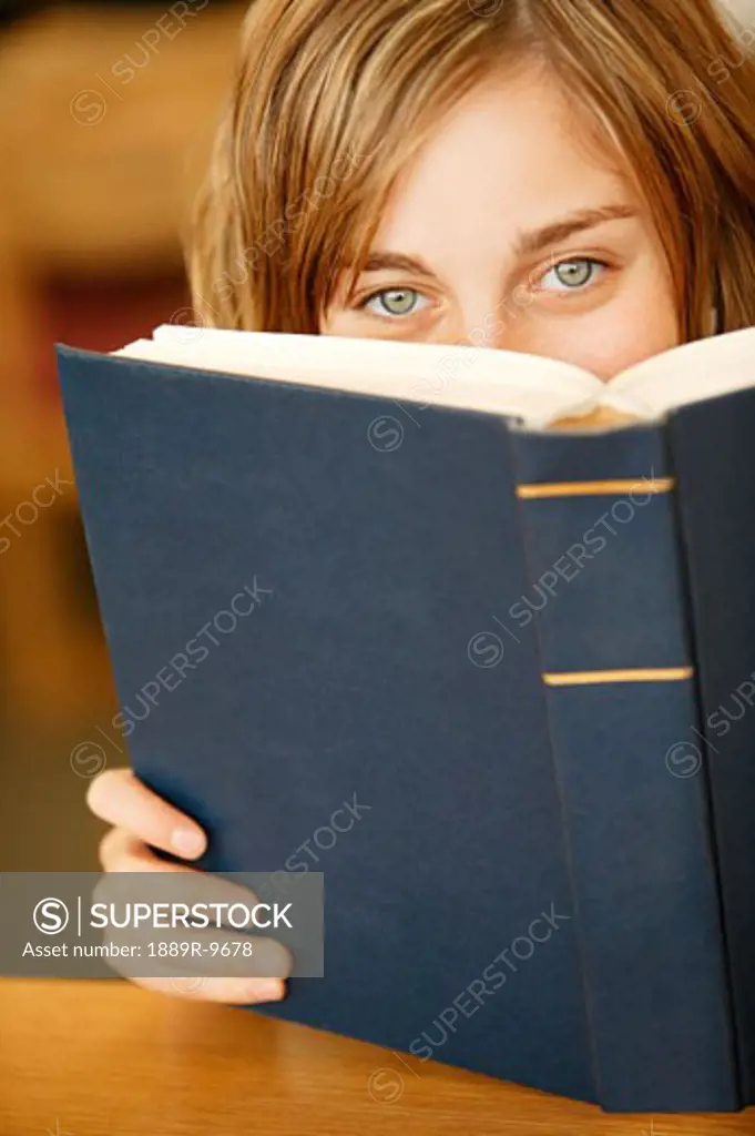 Girl peering over the top of a book
