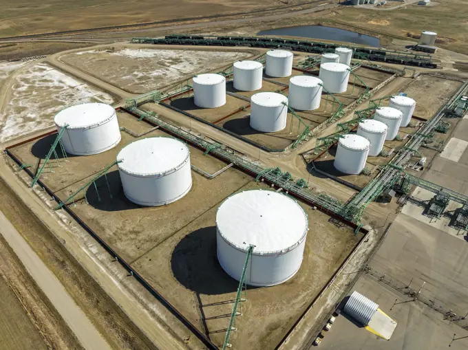 Aerial view of large round metal oil storage tanks with pipelines connecting them, West of Carseland, Alberta; Alberta, Canada