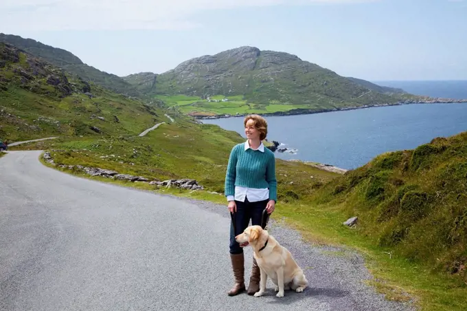 A woman with her dog on a road from eyeries to allihies, county cork ireland