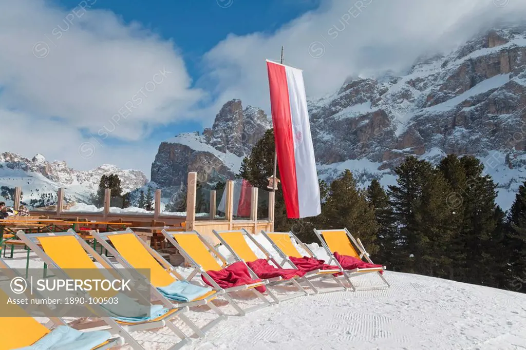 Colourful sun loungers outside a mountain restaurant, Sella Ronda ski area, Val Gardena, Sella Massif under winter snow, Dolomites, South Tirol, Trent...