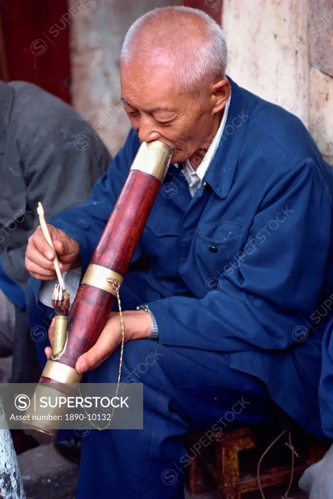 Portrait of a man smoking a long pipe at a tea house in Kunming, China, Asia