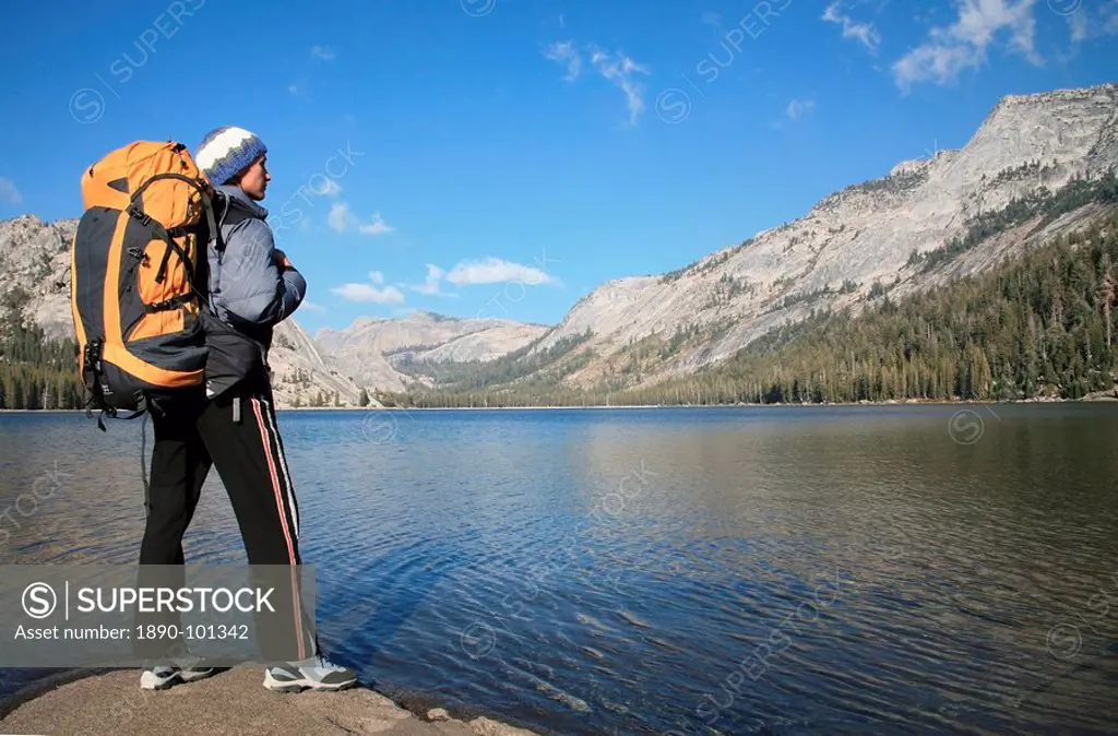A hiker takes in the view on the shore of Tenaya Lake, in the Tuolumne Meadows, near Tioga Pass and Yosemite Valley, Sierra Nevada, California, United...