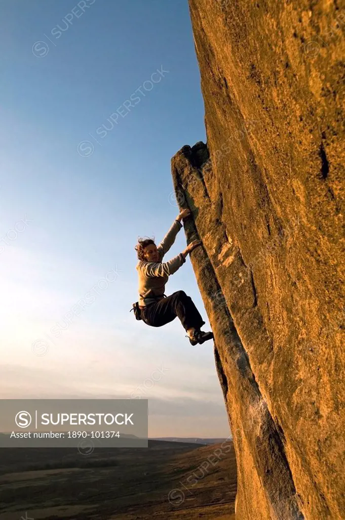 A climber on a popular gritstone bouldering route on the Plantation Boulders at Stanage Edge, Peak District National Park, near Hathersage, Derbyshire...