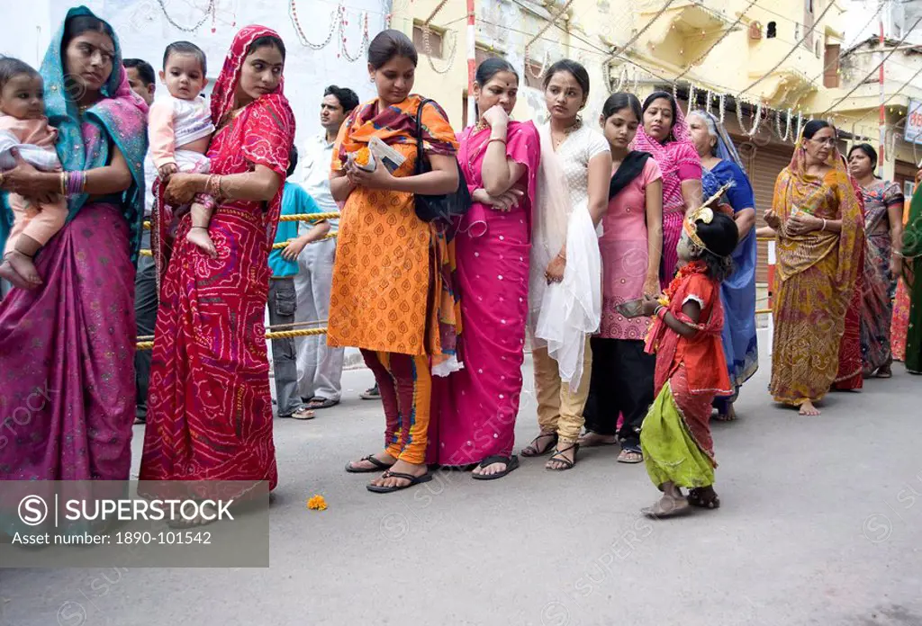 Women queueing for Diwali temple puja, being approached by a child begging for alms, Udaipur, Rajasthan, India, Asia