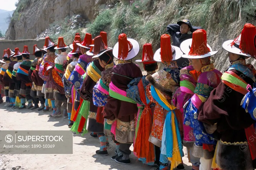 Line of people wearing Tibetan traditional dress, Tongren, Qinghai Province, China, Asia