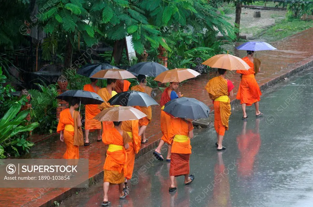 Monks in the rain in Luang Prabang, Luang Prabang, Laos, Indochina, Southeast Asia, Asia