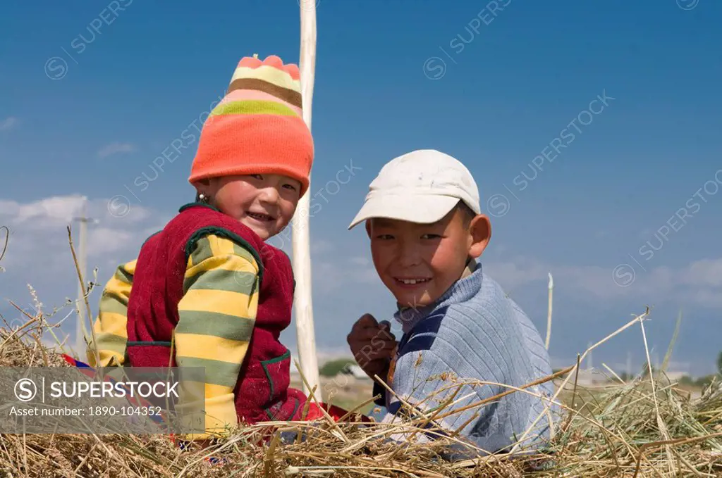Two young kids on a carrier loaded with hay, Torugat Pass, Kyrgyzstan, Central Asia, Asia