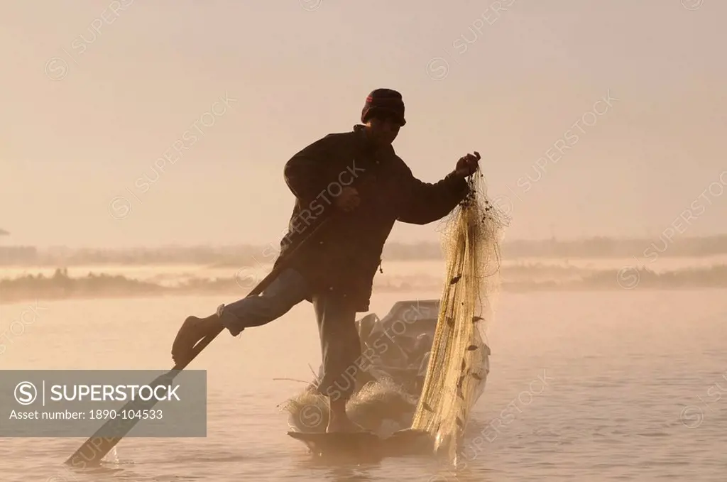 Fisherman holding his fishing net while rowing his little canoe, Inle lake, Myanmar Burma, Asia