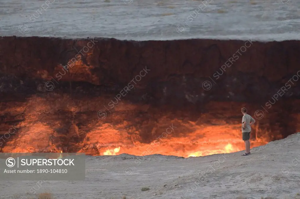 Tourist standing on the edge of the Darvaza Gas crater, Turkmenistan, Central Asia, Asia