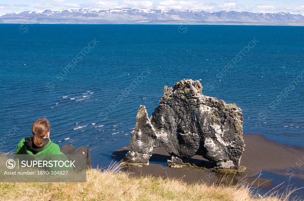 Tourist relaxing at the famous Hvitserkur rock formation, Vatnsnes Peninsula, Iceland, Polar Regions