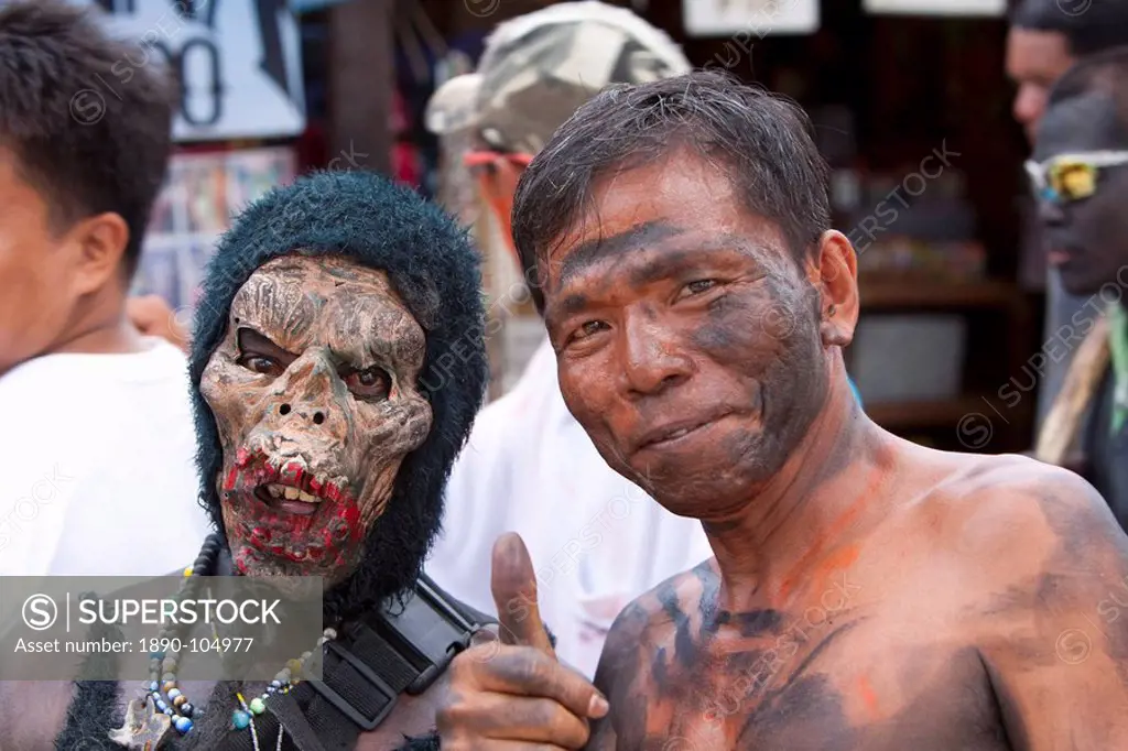 Portrait of two men, one masked, the other with soot smeared on his face during the Ati_Atihan Festival, an annual feast in honour of the Santo Nino, ...