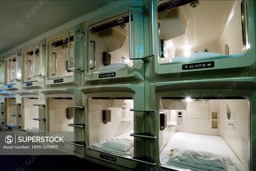 Rows and stacks of sleeping compartments along one corridor at a capsule hotel in Osaka, Japan, Asia