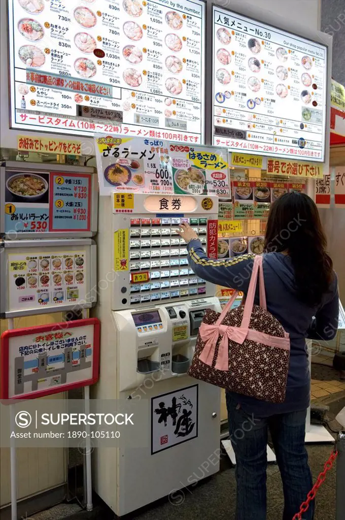 Woman purchasing meal tickets from a vending machine at a restaurant in Dotonbori, Osaka, Japan, Asia