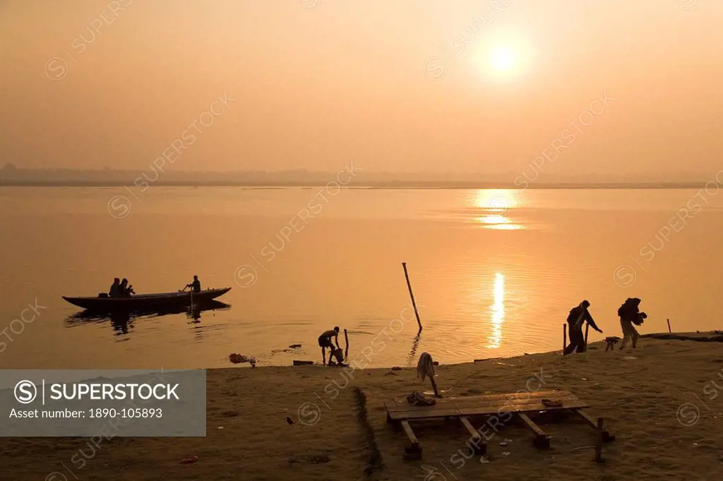 People go about their daily business as the sun rises over the Ganga Ganges River at Varanasi, Uttar Pradesh, India, Asia
