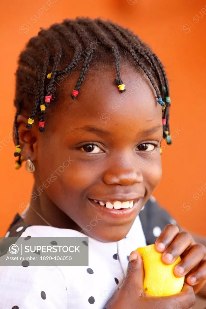 African girl eating an orange, Lome, Togo, West Africa, Africa