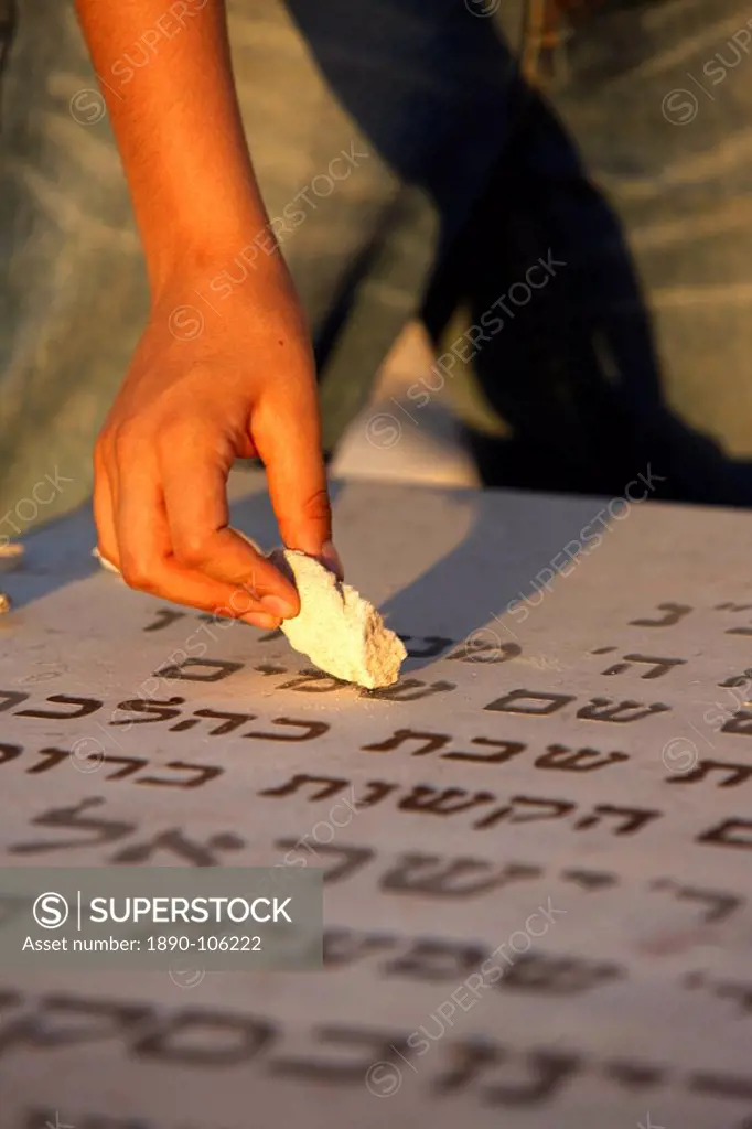 Boy placing stone on a grave in the Mount of Olives Jewish cemetery, Jerusalem, Israel, Middle East