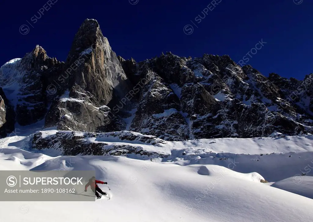A skier enjoying perfect powder snow on the celebrated Pas de Chevre off_piste run, with the Dru in the background, Chamonix Valley, Chamonix, Haute S...