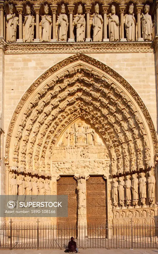 Woman praying in front of Last Judgment gate, west front, Notre Dame Cathedral, UNESCO World Heritage Site, Paris, France, Europe