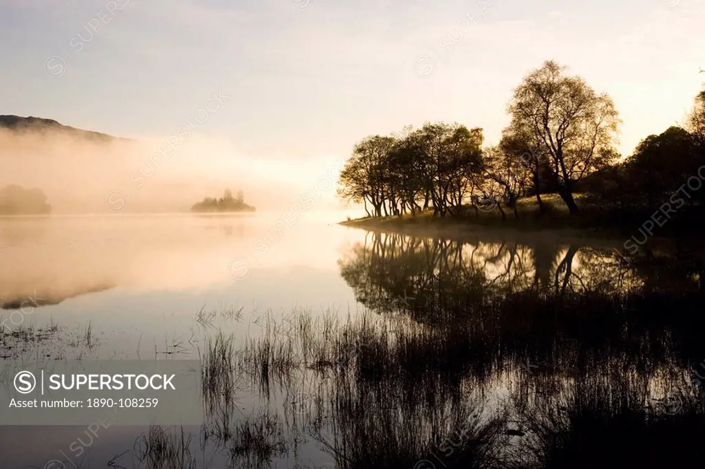 Early morning mist reflected in the still waters of Loch Achray, near Aberfoyle, Loch Lomond and the Trossachs National Park, Stirling, Scotland, Unit...