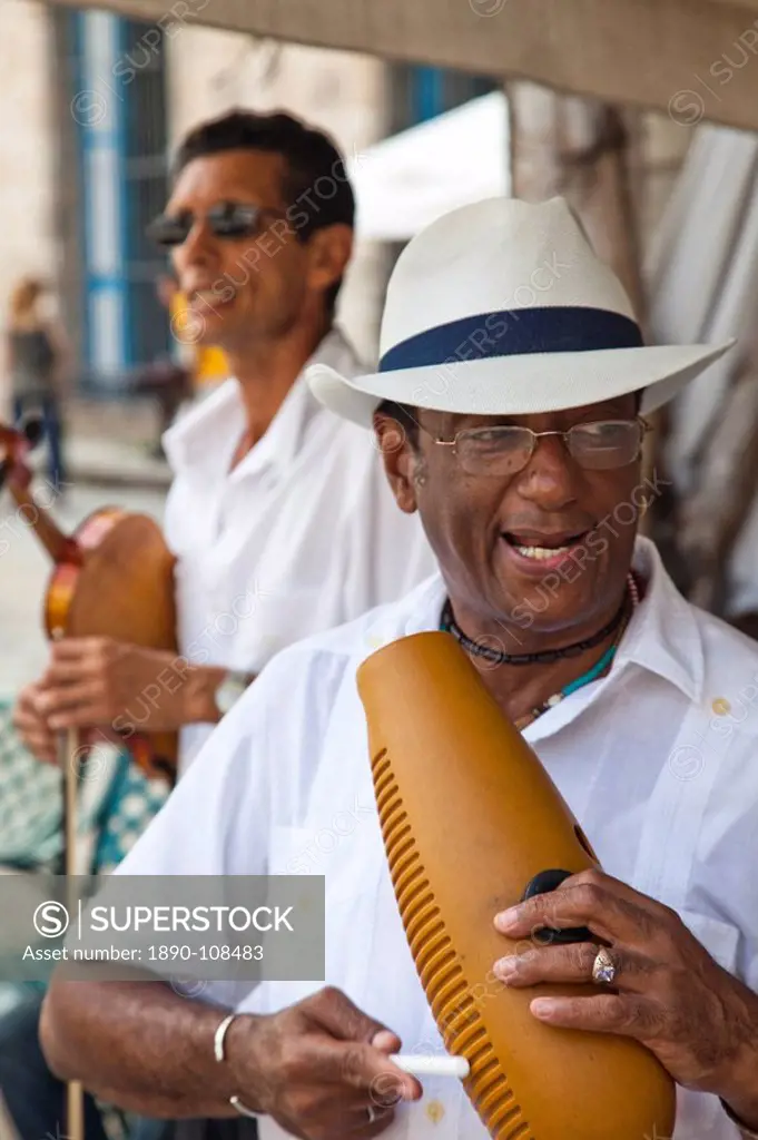 Men playing music on a guiro, a percussive instrument essential in salsa music, and a violin, in Plaza de la Catedral, Havana, Cuba, West Indies, Cent...