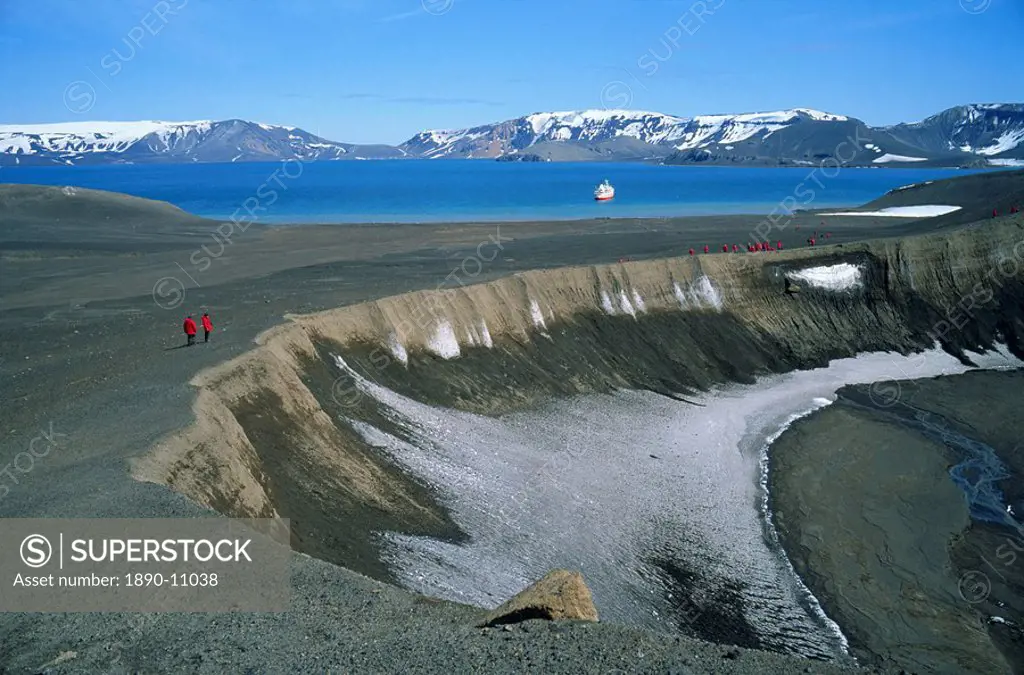 Tourists on rim of volcano, active in 1970, one of two in Antarctica, with cruise ship in the background, on Deception Island, Antarctic Peninsula, An...