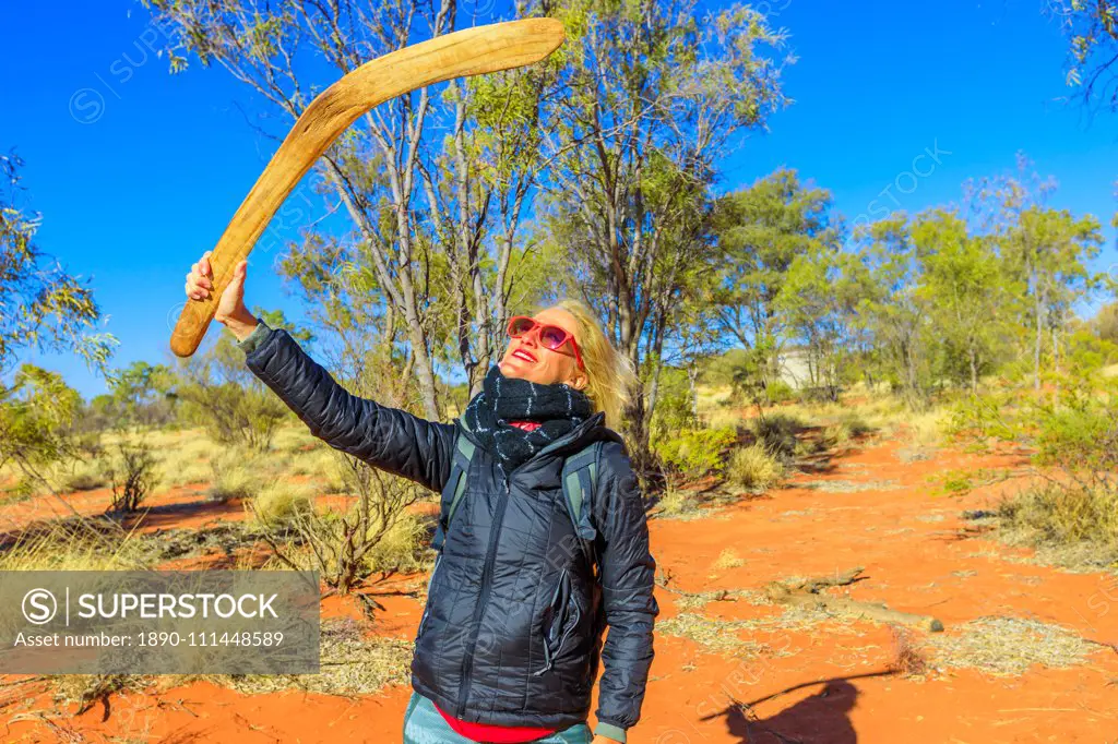 Happy tourist woman holding an aboriginal weapon of boomerang used by Luritja and Pertame people in Central Australia, Northern Territory, Australia, Pacific