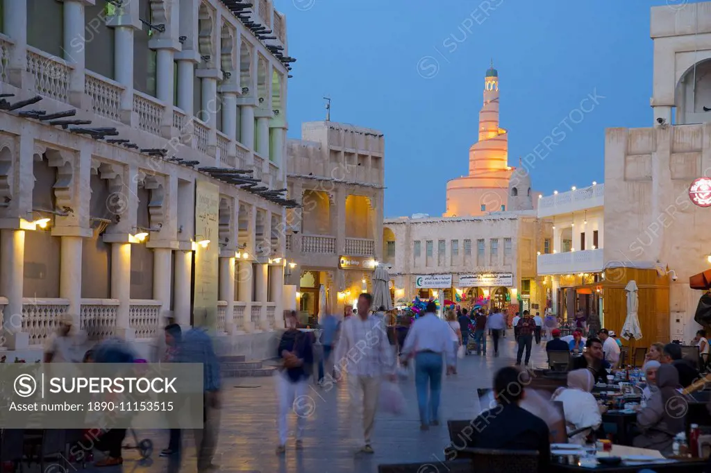 Souq Waqif looking towards the illuminated spiral mosque of the Kassem Darwish Fakhroo Islamic Centre, Doha, Qatar, Middle East