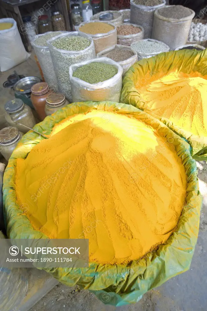 Spice market stall with large bowls of turmeric powder in early morning market on the banks of the Brahmaputra river, Guwahati, Assam, India, Asia