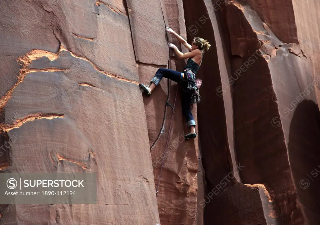 A rock climber tackles an overhanging crack in a sandstone wall on the cliffs of Indian Creek, a famous rock climbing area in Canyonlands National Par...