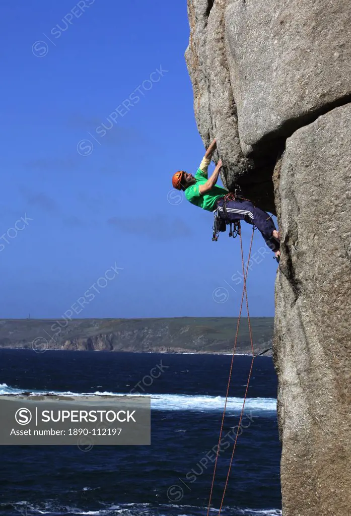 A climber tackles a difficult overhang on the cliffs near Sennen Cove, a popular rock climbing area at Lands End, Cornwall, England, United Kingdom, E...