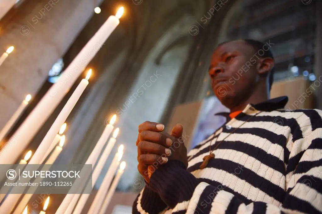 Man praying with candles in church, Amiens, Somme, France, Europe
