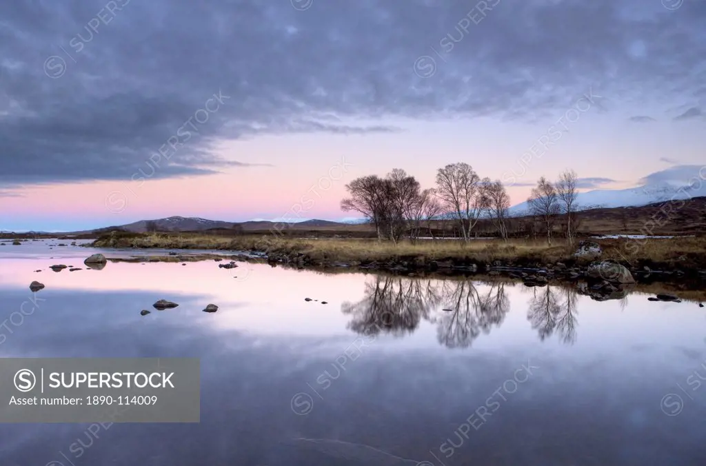 Evening view over flat calm Loch Ba with pink afterglow in sky, reflected in loch and snow_capped mountains in distance, Rannoch Moor, near Fort Willi...