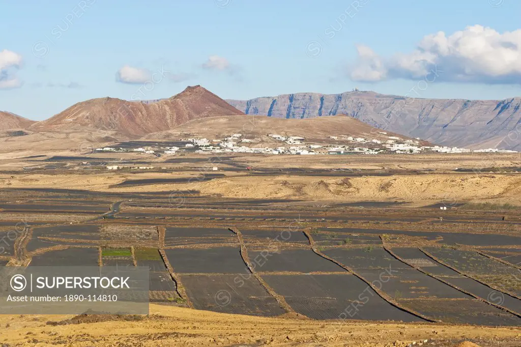 View across black volcanic cinder fields to the town of Soo and the Risco de Famara range with the highest point on the island at Penas del Cache rada...