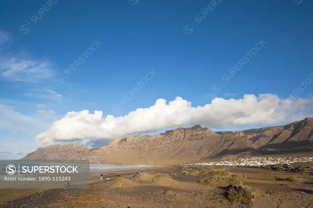 Spectacular 600m volcanic cliffs of the Risco de Famara rising over Lanzarote´s finest beach at Famara, with its low_rise bungalow development, Famara...