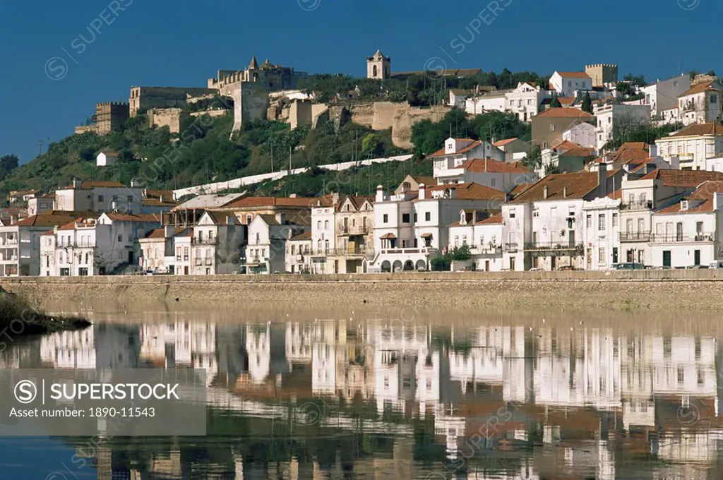 View of town and castle ramparts, reflected in Sado River, Alcacer do Sal, Portugal, Europe