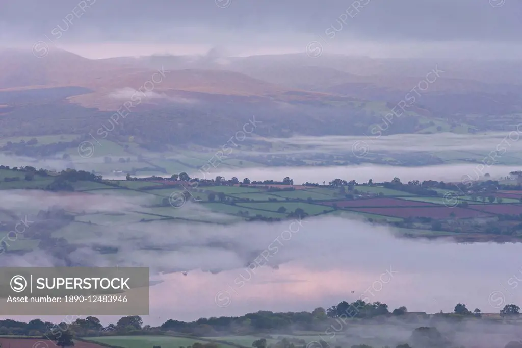 Early morning mist drifts above Llangorse Lake and the rolling fields of the Brecon Beacons National Park, Powys, Wales, United Kingdom, Europe