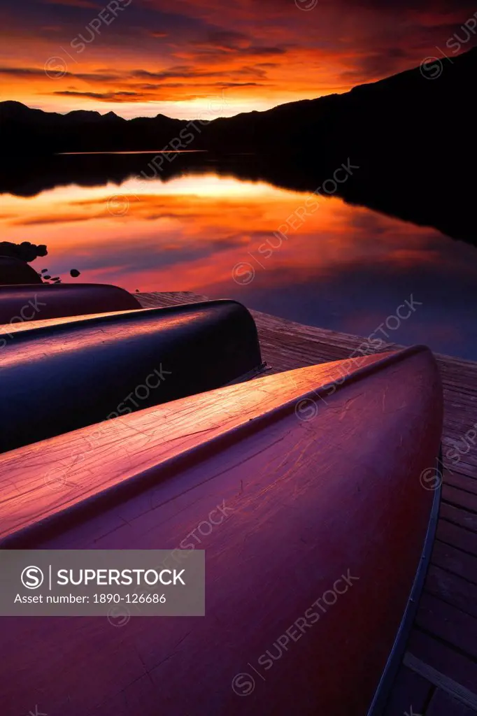 Lined up canoes reflect the colours of a stunning sunset, Canada, North America