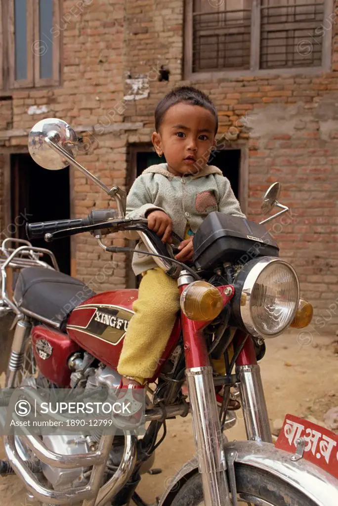 Portrait of young child sitting on motorcycle, Kathmandu, Nepal, Asia