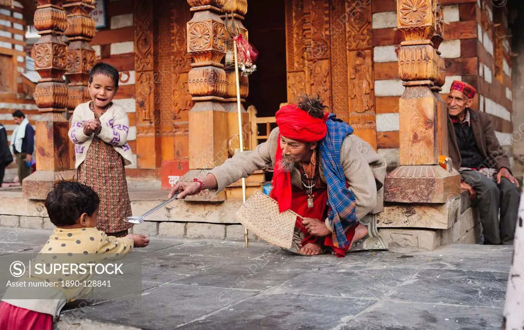 Priest giving sweets to small boy outside Hindu temple, Manali, Himachal Pradesh, India, Asia