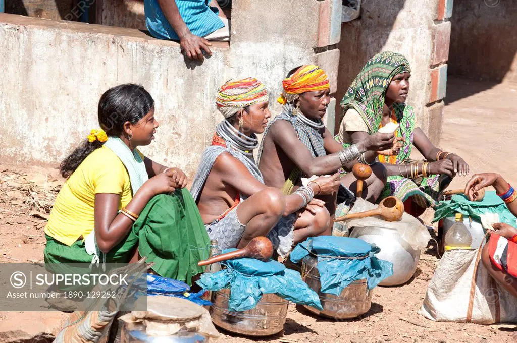 Bonda tribeswomen wearing traditional beaded caps and metal necklaces, selling village_made alcohol at weekly market, Rayagader, Orissa, India, Asia