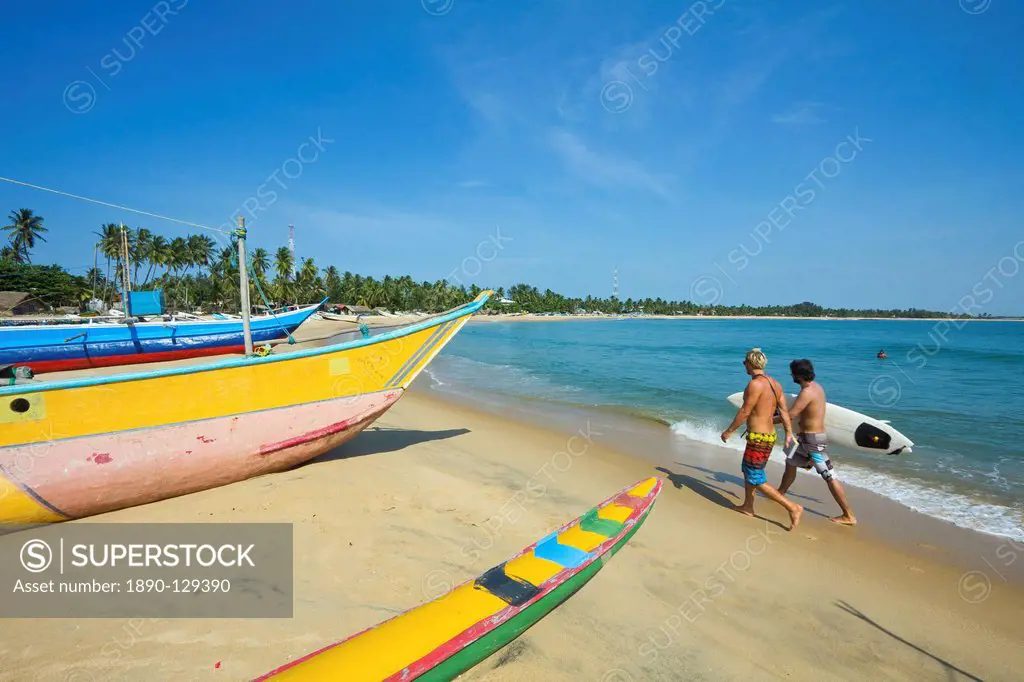 Surfers and fishing boats on this popular surf beach, badly hit by the 2004 tsunami, Arugam Bay, Eastern Province, Sri Lanka, Asia