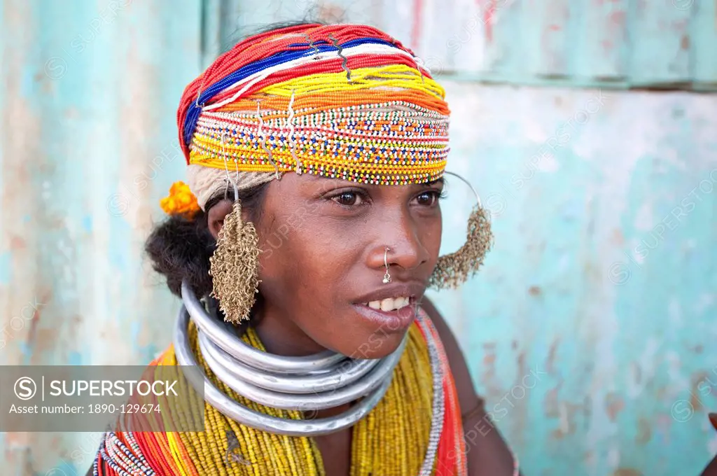Bonda tribeswoman wearing traditional bead costume with beaded cap, large earrings, nose ring and metal necklaces at weekly market, Rayagader, Orissa,...